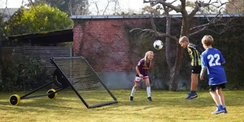 kid practicing football with  m-station soccer kickback net trampoline rebounder by Munin Sports